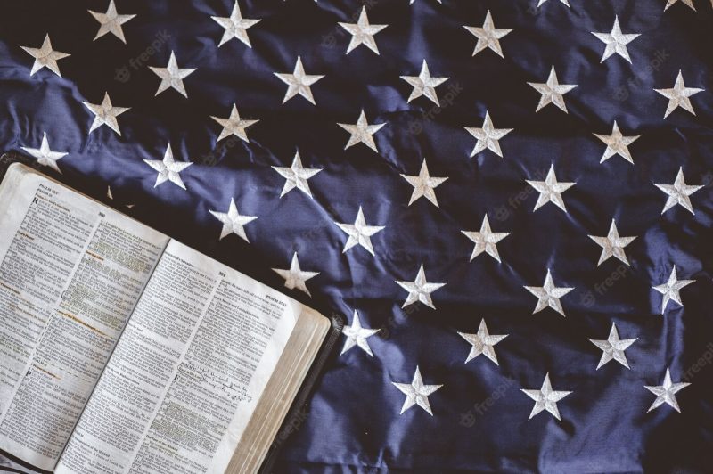 Closeup shot of the bible open in pages put on the american flag – perfect for praying concept Free Ph