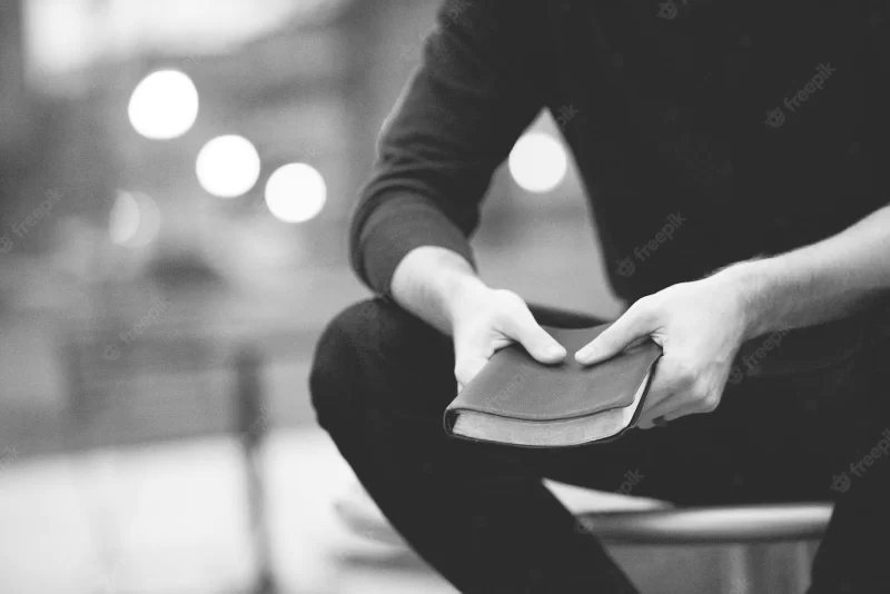 Closeup shot of a male holding the bible with a blurred background in black and white Free Photo