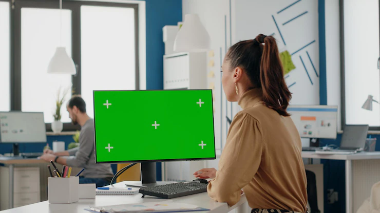 Company worker using computer with green screen in office. business woman working with mock up isolated template and chroma key blank background. greenscreen app on monitor with copy space Free Photo