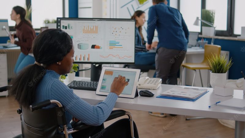 Handicapped woman entrepreneur with locomotor disabilities using computer and tablet in same time