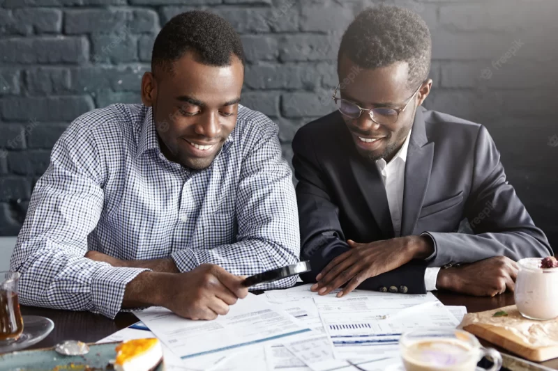 Happy african american office workers dressed in formal clothing having cheerful looks, studying and