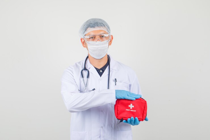 Male doctor holding first aid kit in protective clothes and looking careful Free Photo