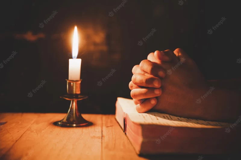 Man praying on the bible in the light candles selective focus Free Photo