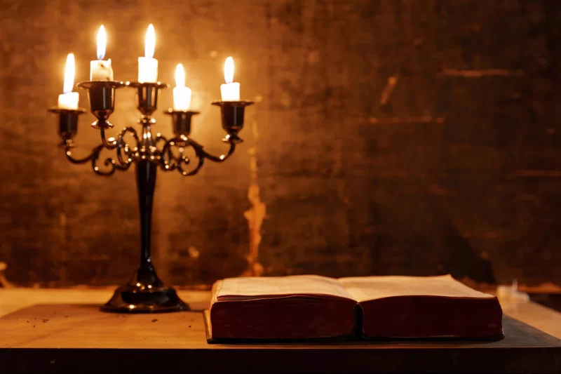 Open holy bible and candle on a old oak wooden table. beautiful gold background. religion concept. F