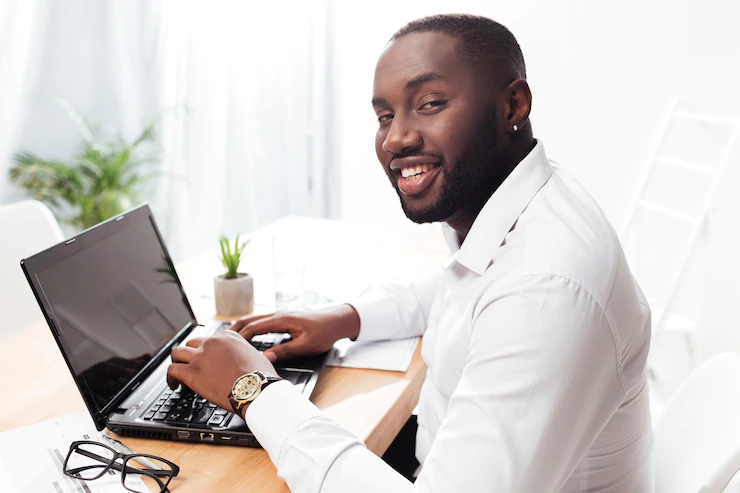 Portrait Smiling African American Businessman White Shirt Sitting Happily Looking Camera While Working His Laptop Office Isolated 574295 3254