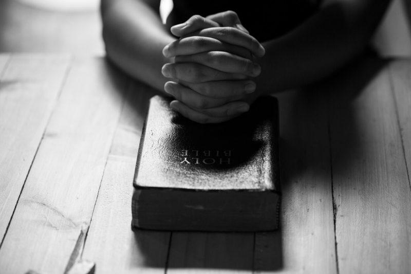 Praying hands of teens on old bible Free Photo