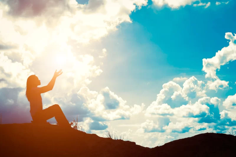 Silhouette of woman with raised hands Free Photo