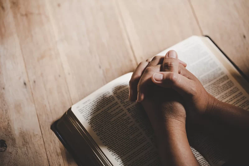 Spirituality and religion, hands folded in prayer on a holy bible in church concept for faith. Free Phot