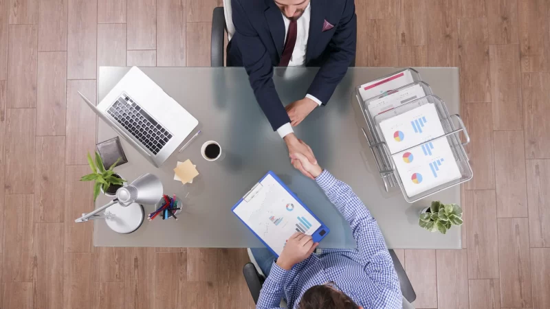 Top view of businessmen shaking hands during business negotiation in startup office Free Photo