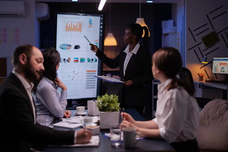 Workaholic african american leader standing in front of presentation monitor explaining marketing pr