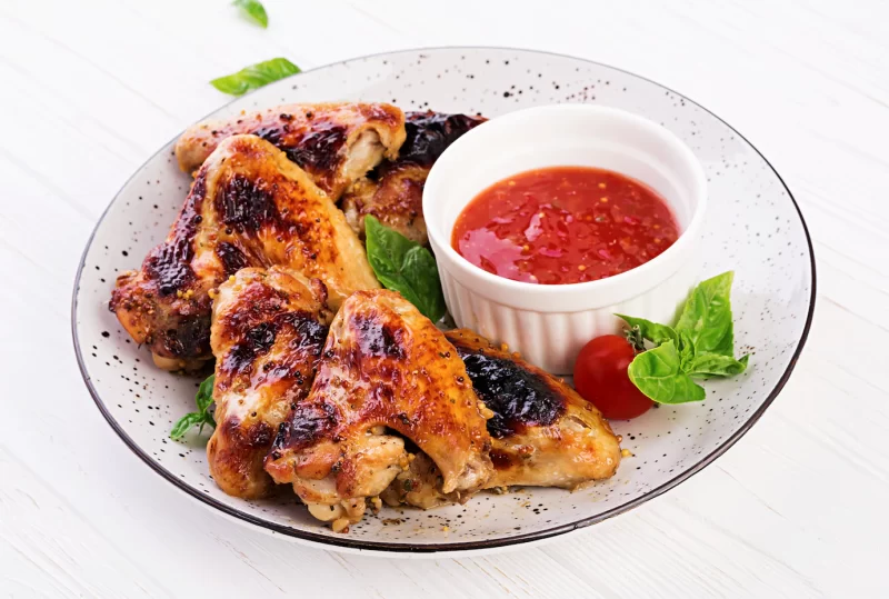 Baked chicken wings in the asian style and tomatoes sauce on plate Free Photo