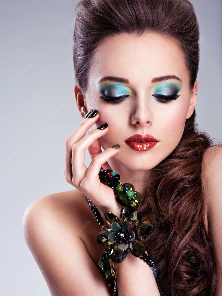 Beautiful woman face with fashion green make-up and jewelry on hand Free Photo