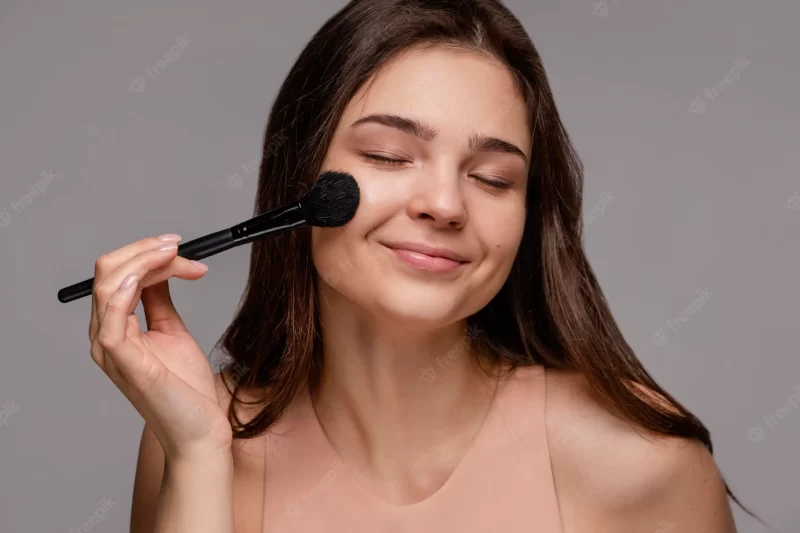 Brunette woman using a make-up brush Free Photo