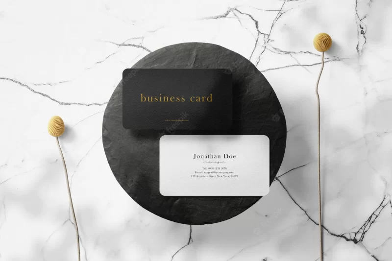 Clean minimal business card mockup on black stone plate with flower plants background. psd file. Free Psd