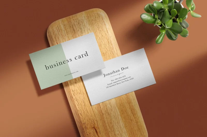 Clean minimal business card mockup on wooden plate with plant Free Psd