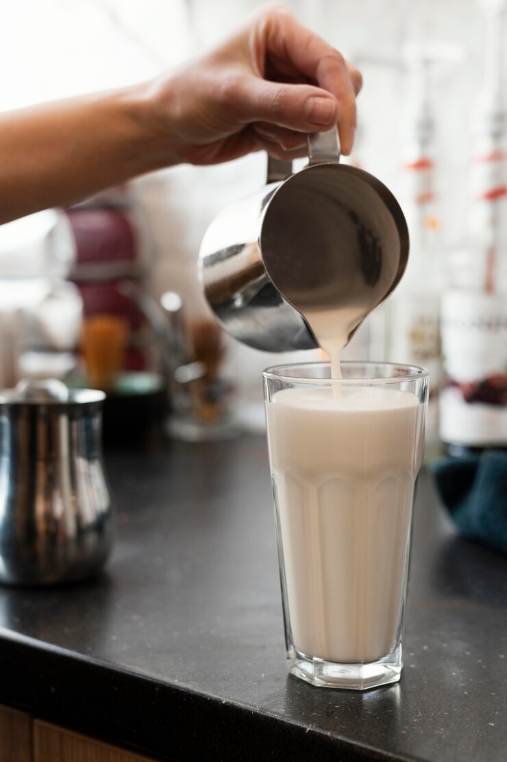 Close up hand pouring tasty milk in glass Free Photo