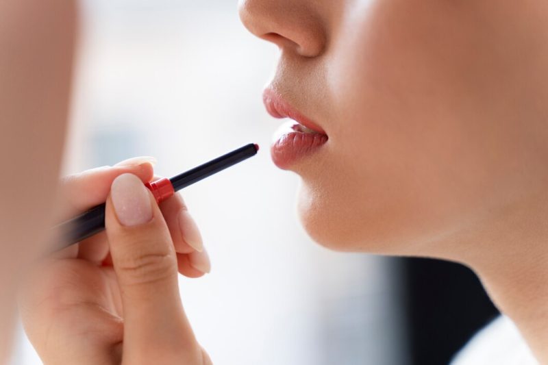 Close up woman applying lipstick Free Photo