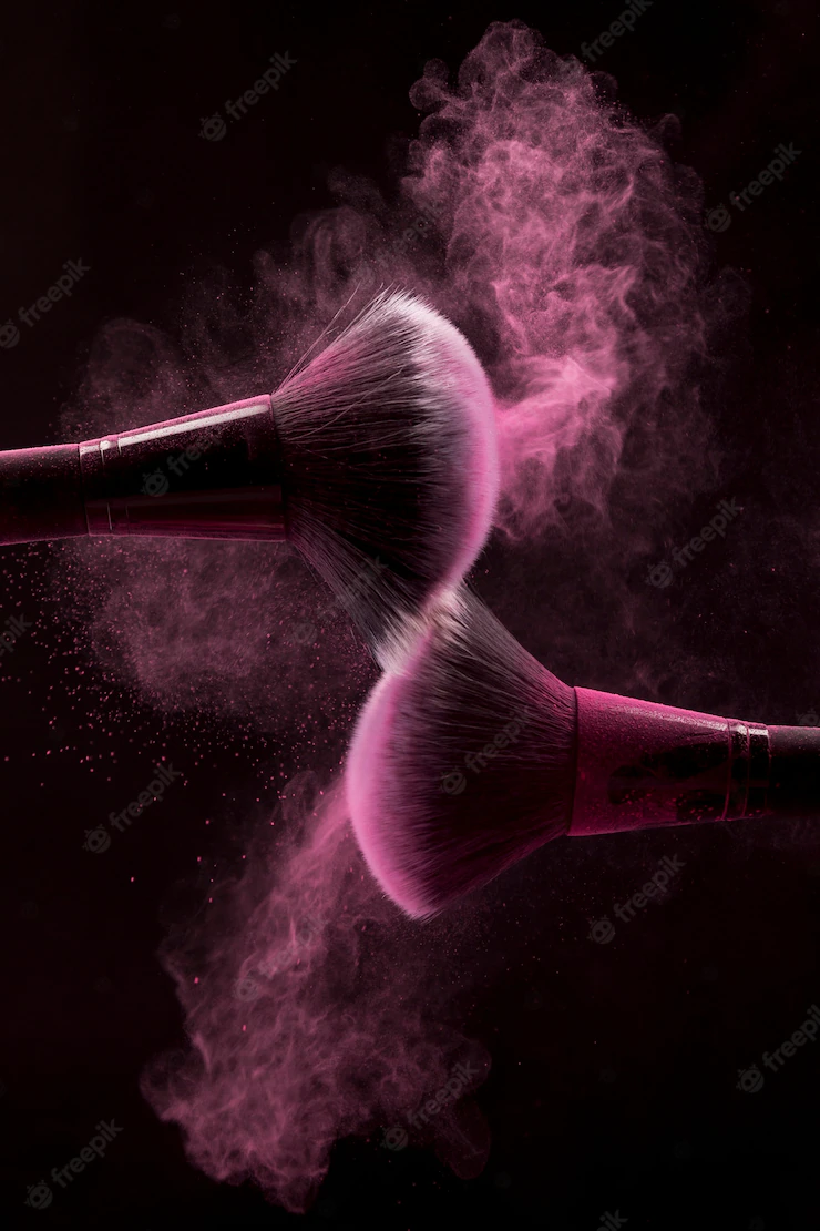 Cosmetic brushes in pink mist of powder on dark background Free Photo