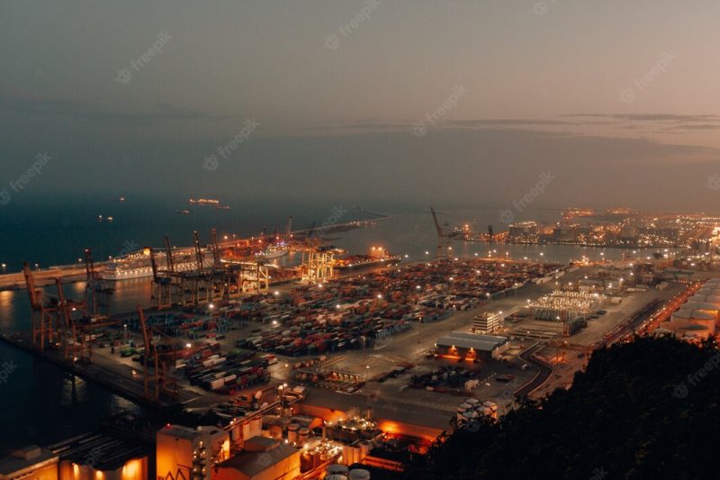 Distant shot of a port with boats loaded with cargo and shipment during nighttime Free Ph