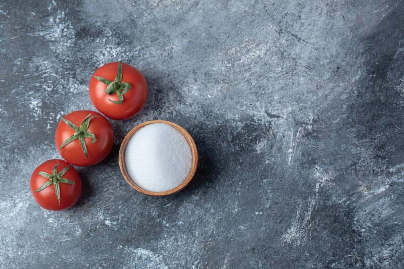 Fresh red tomatoes with a wooden bowl full of salt. Free Photo