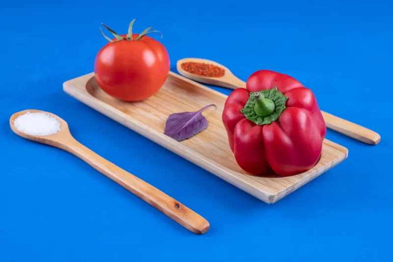 Fresh tomato and red bell pepper on wooden plate with spices Free Photo