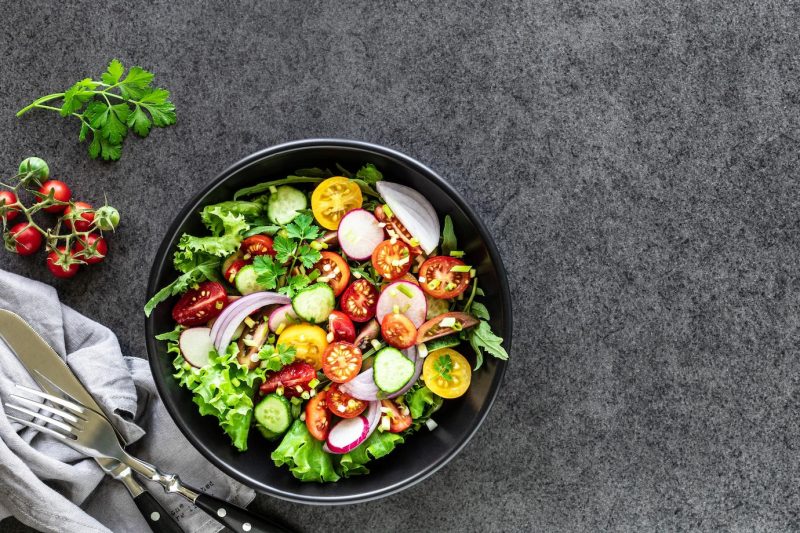 Fresh vegetable salad in a plate on a black background. top view Free Photo