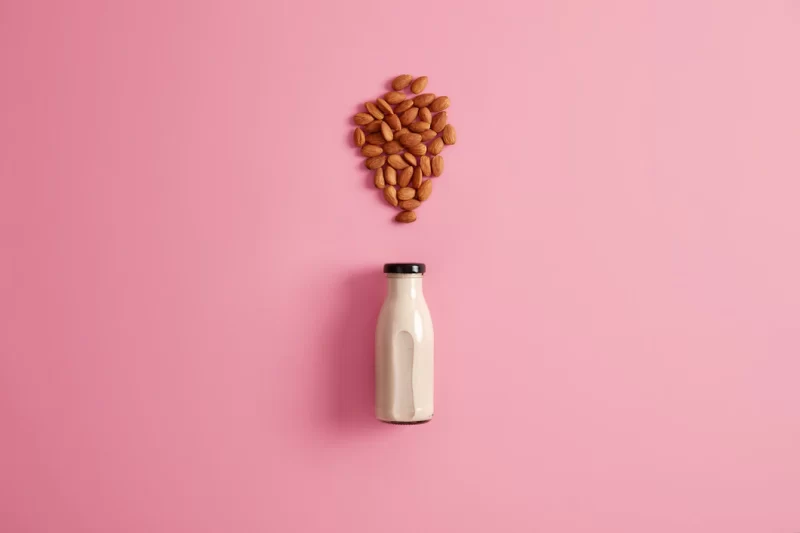 Freshly maked almond milk in glass bottle to substitute dairy product for vegetarians. rosy background, top view. healthy vegetarian natural drink. diet, health care, proper nutrition concept Free Photo