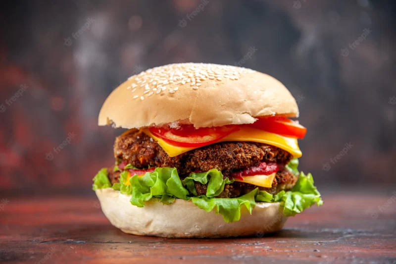 Front view tasty meat burger with cheese and salad on dark background Free Photo