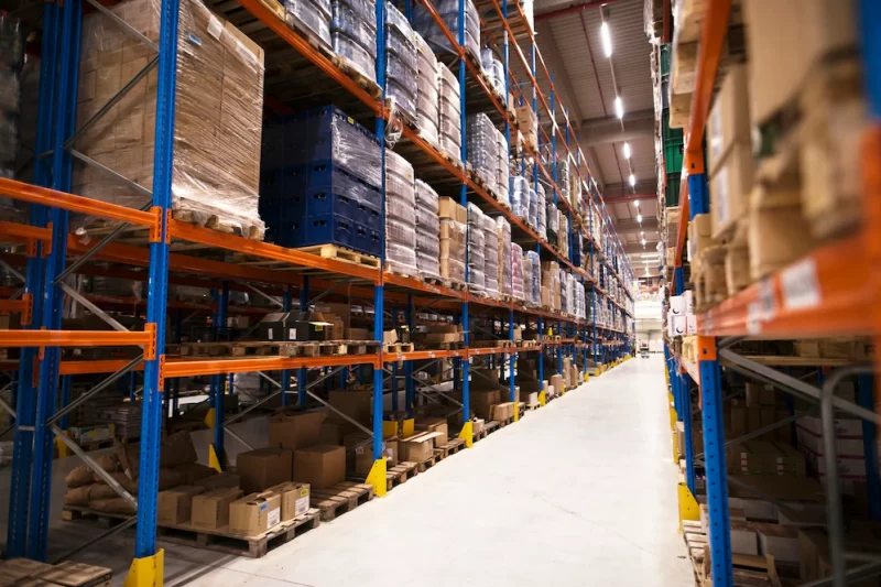 Interior of large distribution warehouse with shelves stacked with palettes and goods ready for the market Free Photo