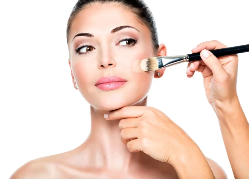 Makeup artist applying liquid tonal foundation on the face of the woman Free Photo