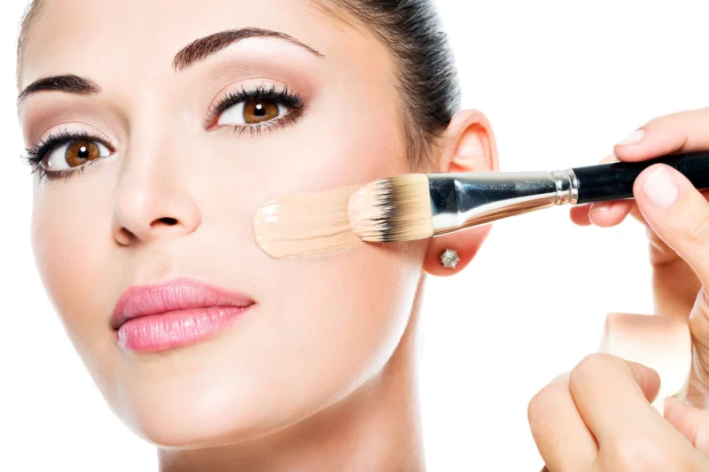 Makeup artist applying liquid tonal foundation on the face of the woman Free Photo