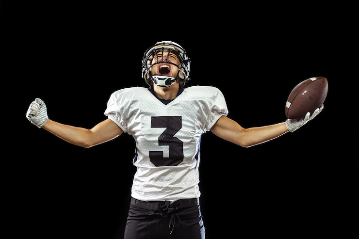 Portrait of american football player in sports equipment isolated on black Free Photo