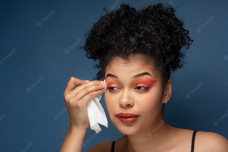 Portrait of a gorgeous woman removing her make-up with a make-up remover tissue Free Photo