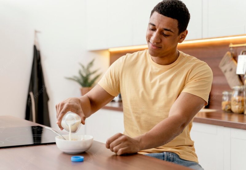 Portrait man at home pouring milk in bowl Free Photo