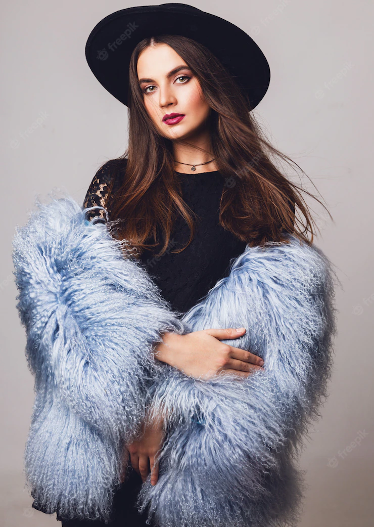 Portrait of pretty young model in stylish winter fluffy coat and black hat posing Free Photo