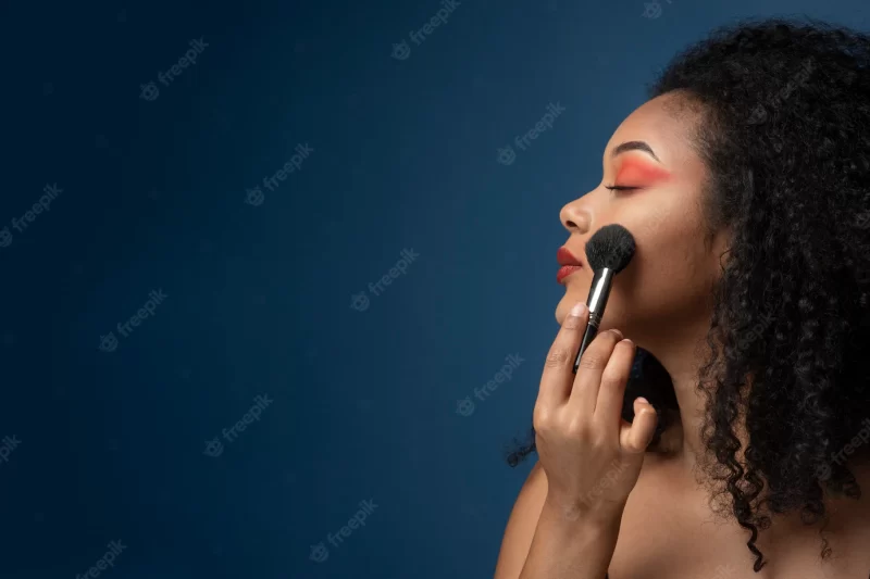 Portrait of a woman applying make up with a make-up brush Free Photo