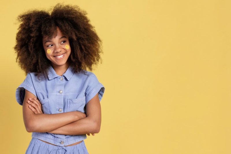 Portrait of young adorable girl posing with emoji stickers on her face Free Photo