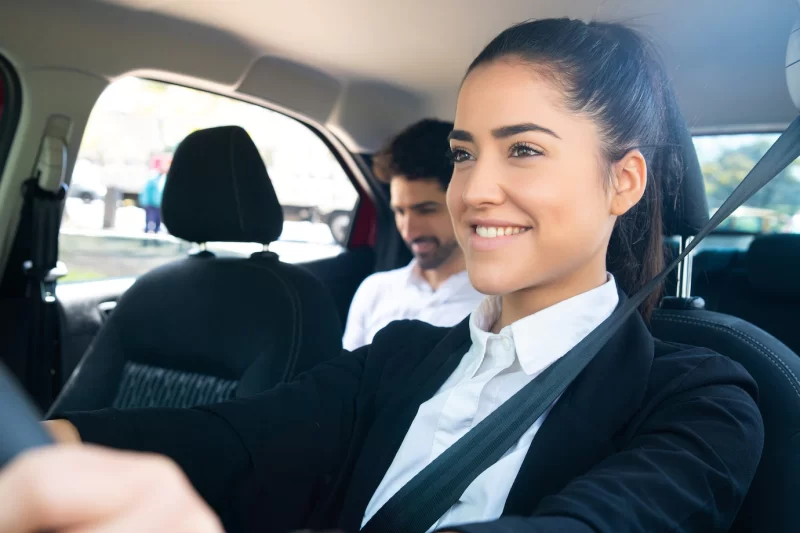 Portrait of young female taxi driver with a businessman passenger at back seat Free Photo