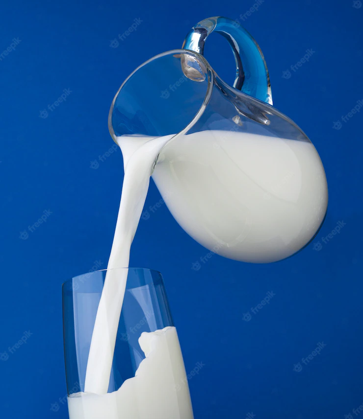 Pouring milk with splash on blue background Premium Photo