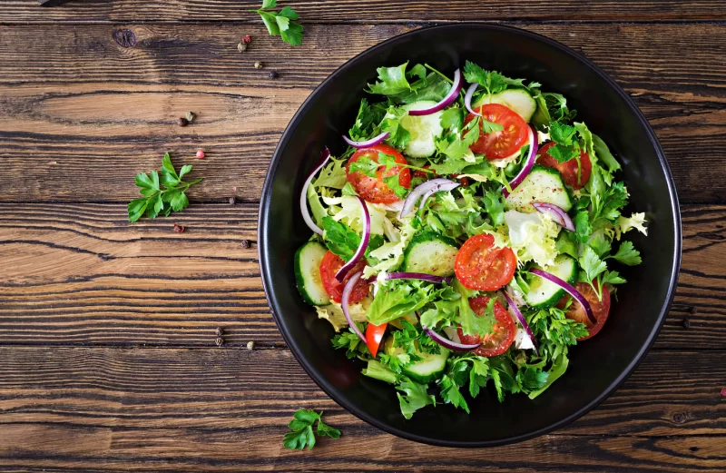 Salad from tomatoes, cucumber, red onions and lettuce leaves. healthy summer vitamin menu. vegan vegetable food. vegetarian dinner table. top view. flat lay Free Photo