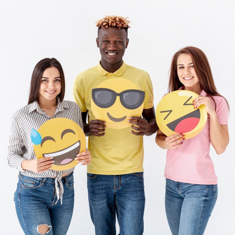 Smiley young friends holding emoji Free Photo