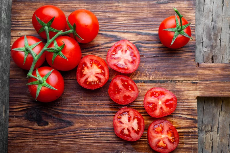 Some tomatoes and slices with knife on a wooden cutting board top view. Free Photo