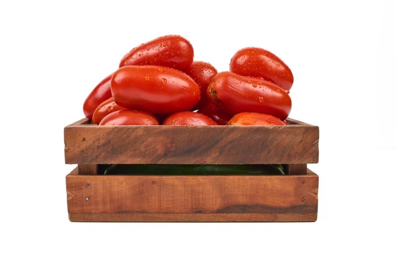 Tomatoes in wooden tray on the white. Free Photo