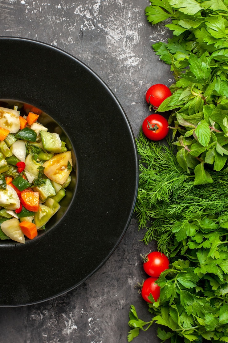 Top close view green tomato salad on oval plate greens tometoes on dark background Free Photo