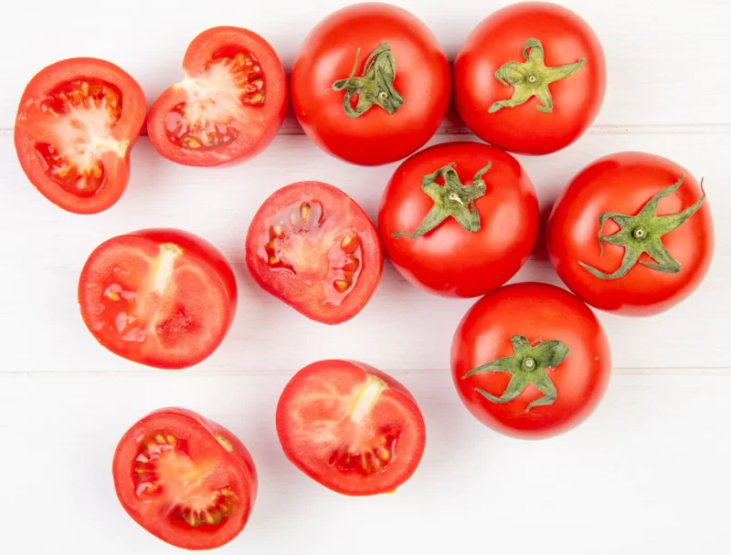 Top view of cut and whole tomatoes on wooden surface Free Photo