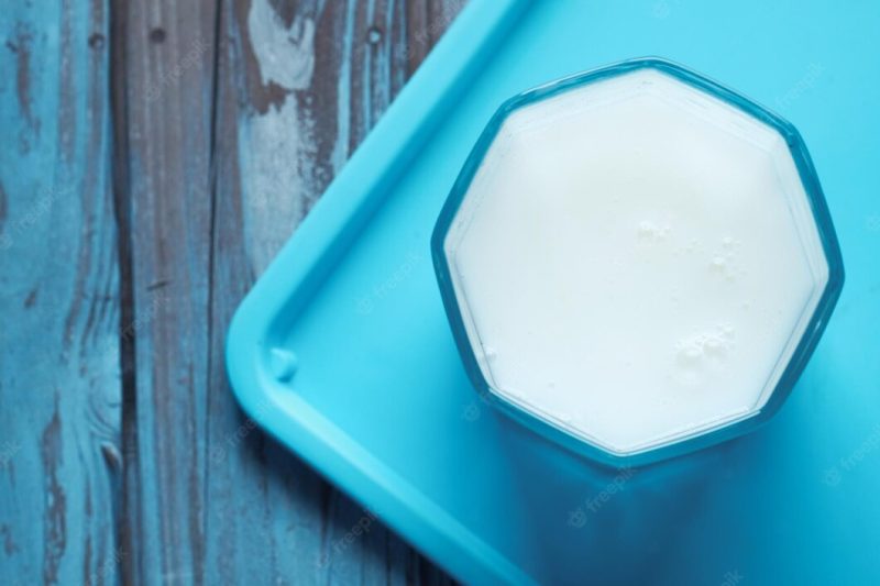 Top view of pouring milk into the glass on wood table Premium Photo