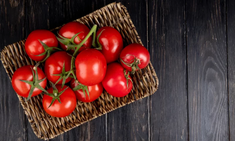 Top view of tomatoes in basket plate on wood with copy space Free Photo