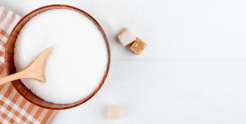 Top view of white sugar in a wooden bowl with a spoon and lump sugar cubes on white background with copy space Free Photo