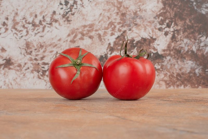 Two fresh tomatoes isolated on marble table. Free Photo