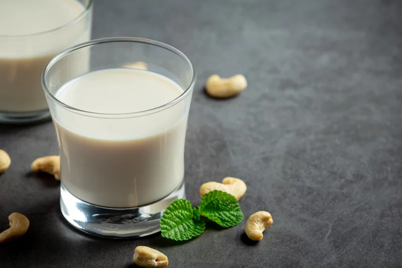 Vegan cashew milk in glass with cashews nuts on dark background Free Photo